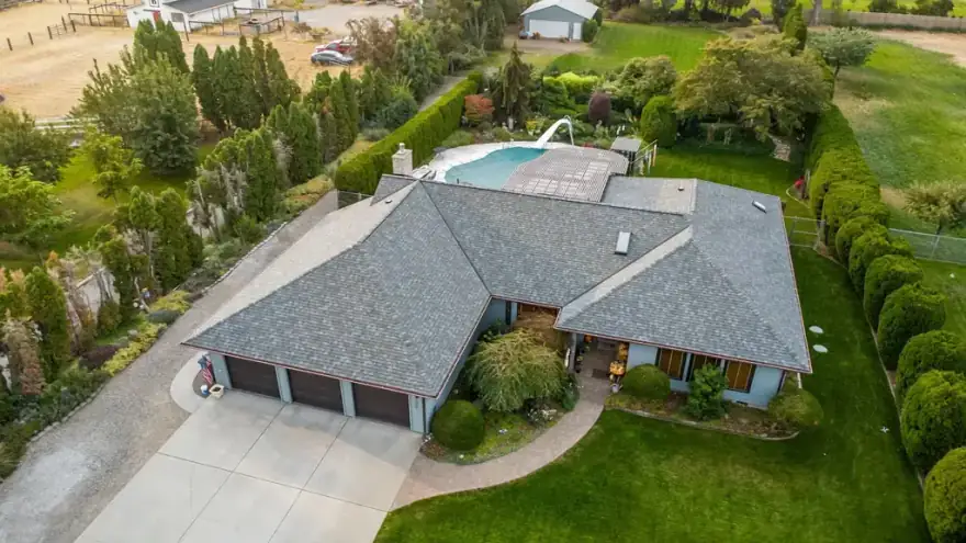 Drone view of a finished grey shingle roof on a ranch home with a pool