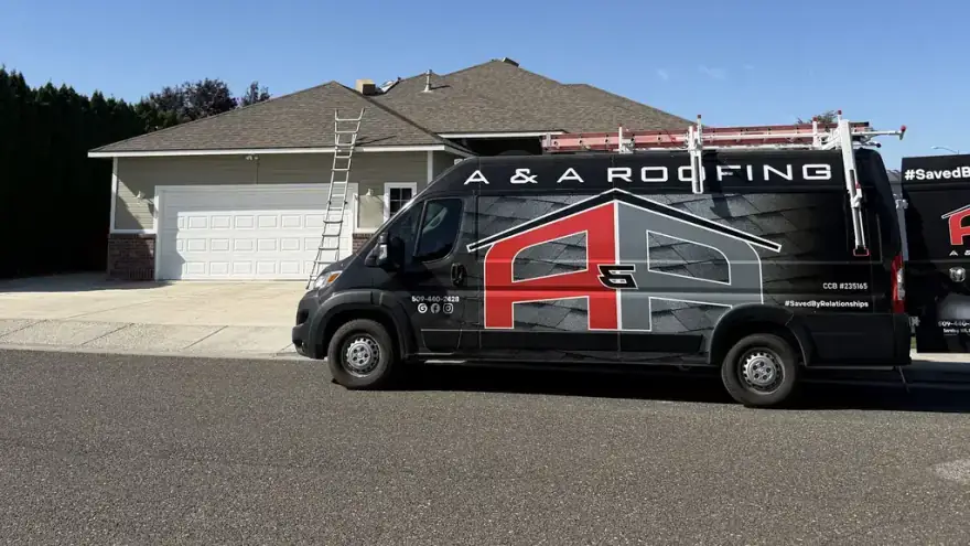 The A&A van in its black, red and grey wrap, parked at a finished home with a ladder up
